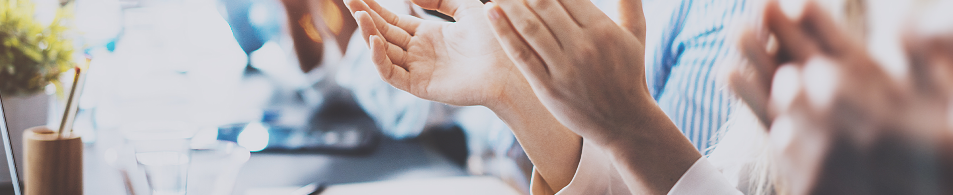 A photo showing only the hands of a group of people clapping in celebration.