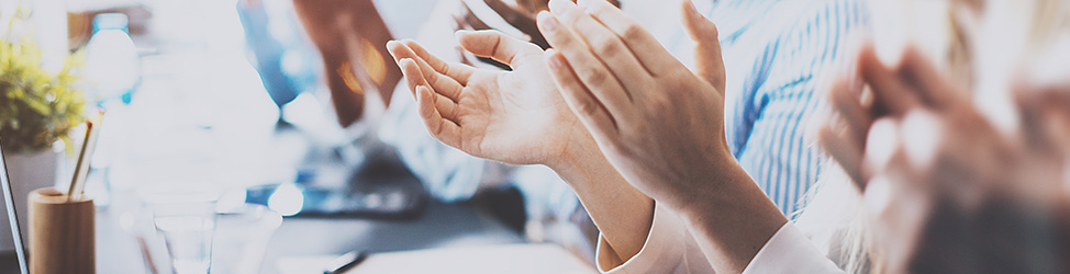 A photo showing only the hands of a group of people clapping in celebration.