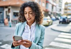 A woman walking down a street while looking at her phone.