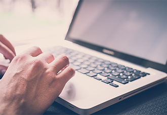 A photo showing only the hands of a person typing on a laptop.