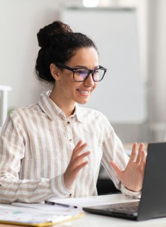 A female worker smiling while video chatting on her laptop.