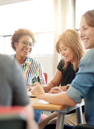 A photo of female students smiling and studying together.