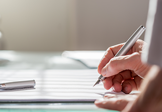 A photo focusing on a person’s hand writing on a notebook with a fountain pen.