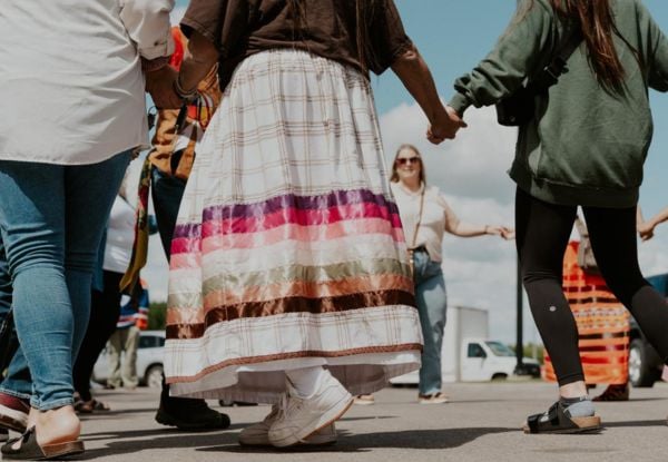 A photo of Indigenous students and family walking around in a circle and smiling.