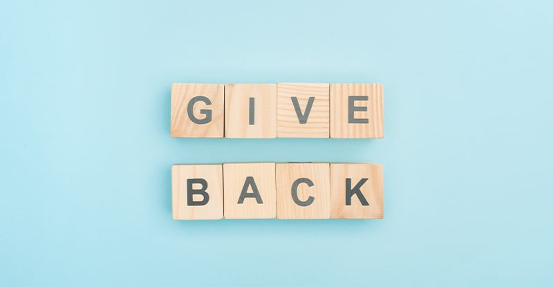 A photo of a light blue background with letter blocks that read " Give back".