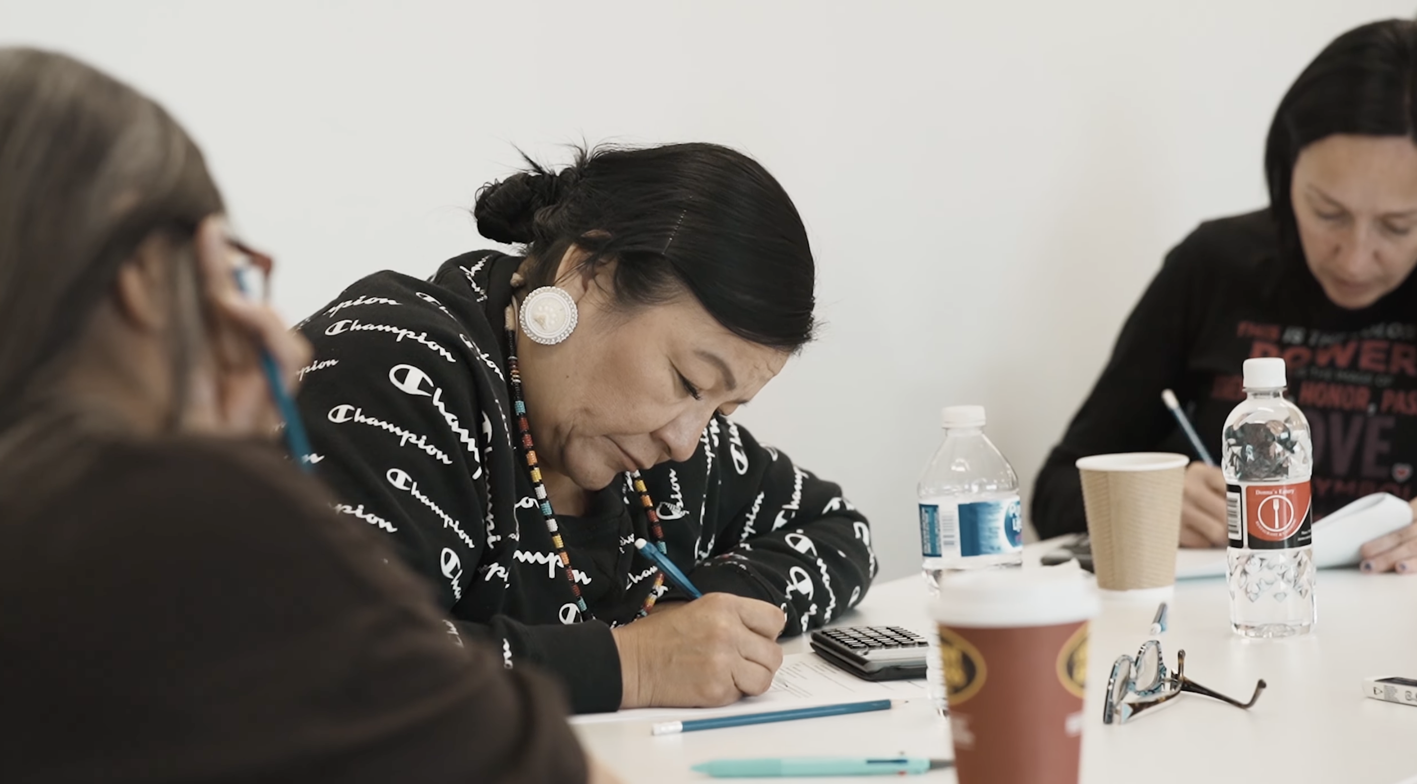 A photo taken at an Indigenous course, showing potential students intently listening and taking notes.