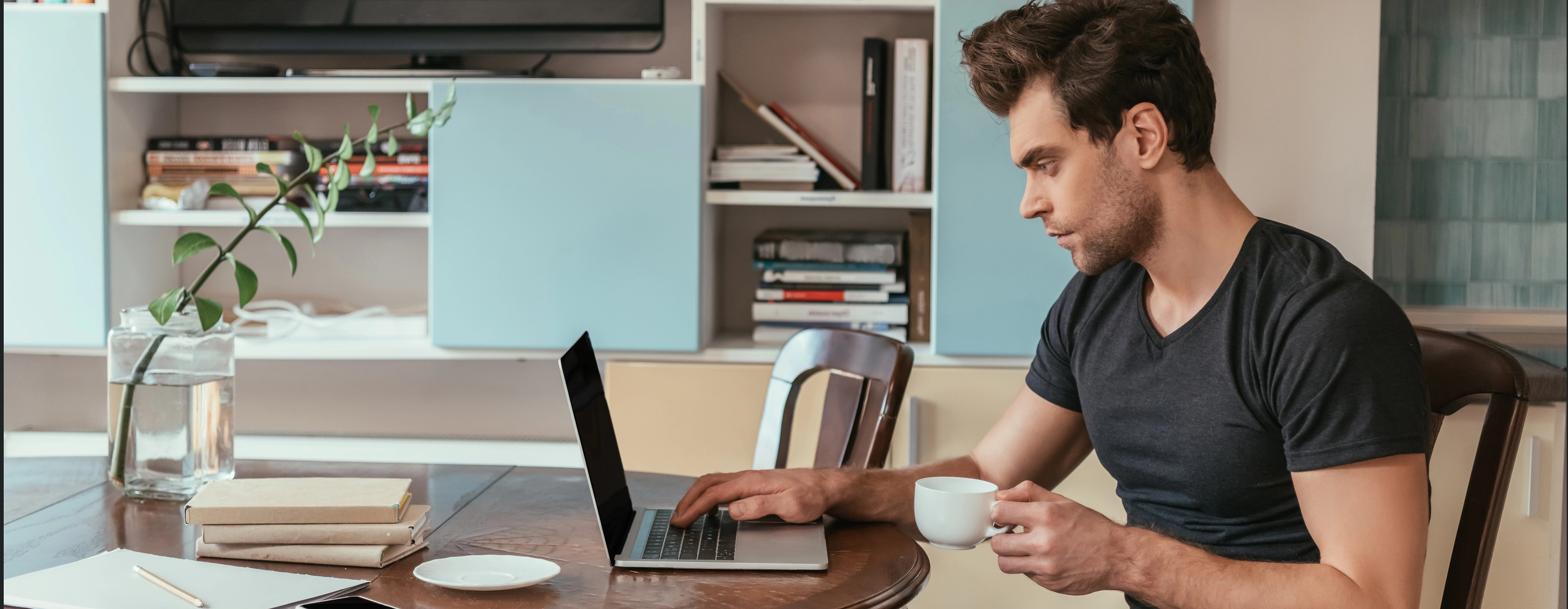 a man sitting at a table with a laptop and a cup of coffee