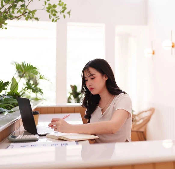 a woman sitting at a desk writing on a book