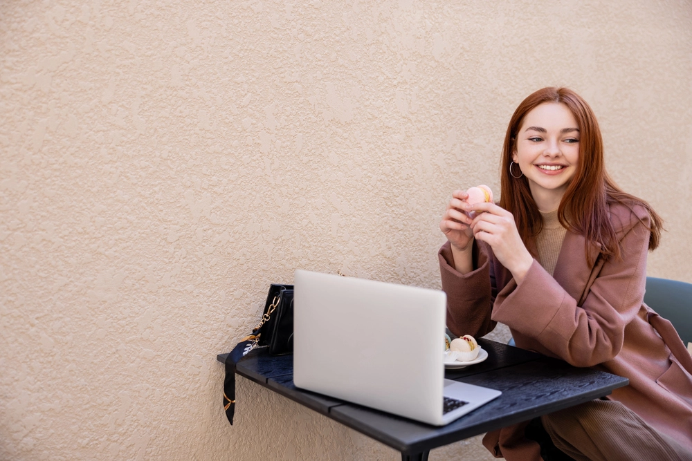 a woman sitting at a table with a laptop and food