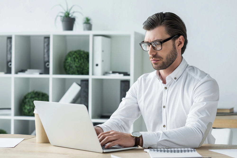 a man sitting at a desk using a laptop