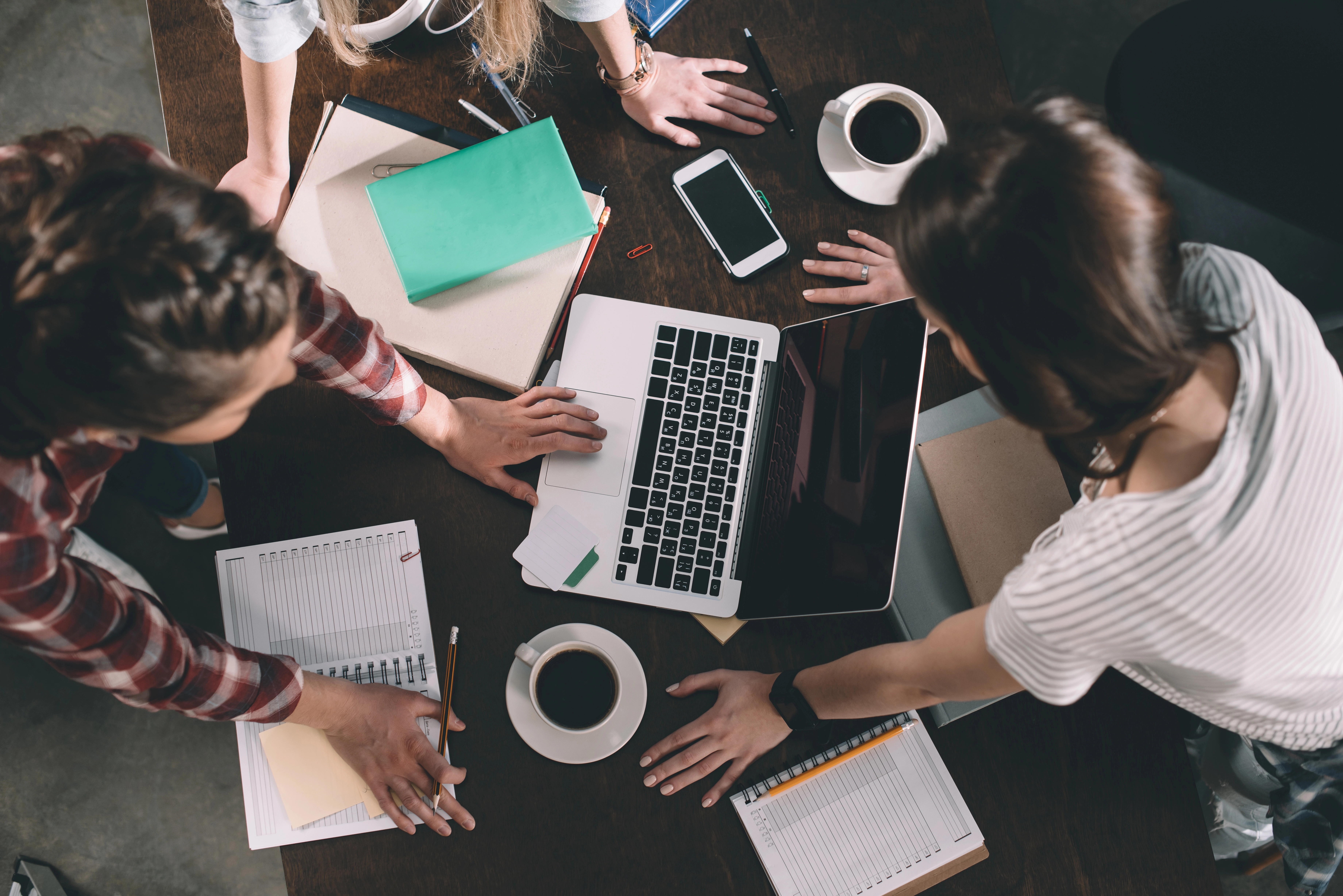 a group of people sitting around a table with a laptop and coffee