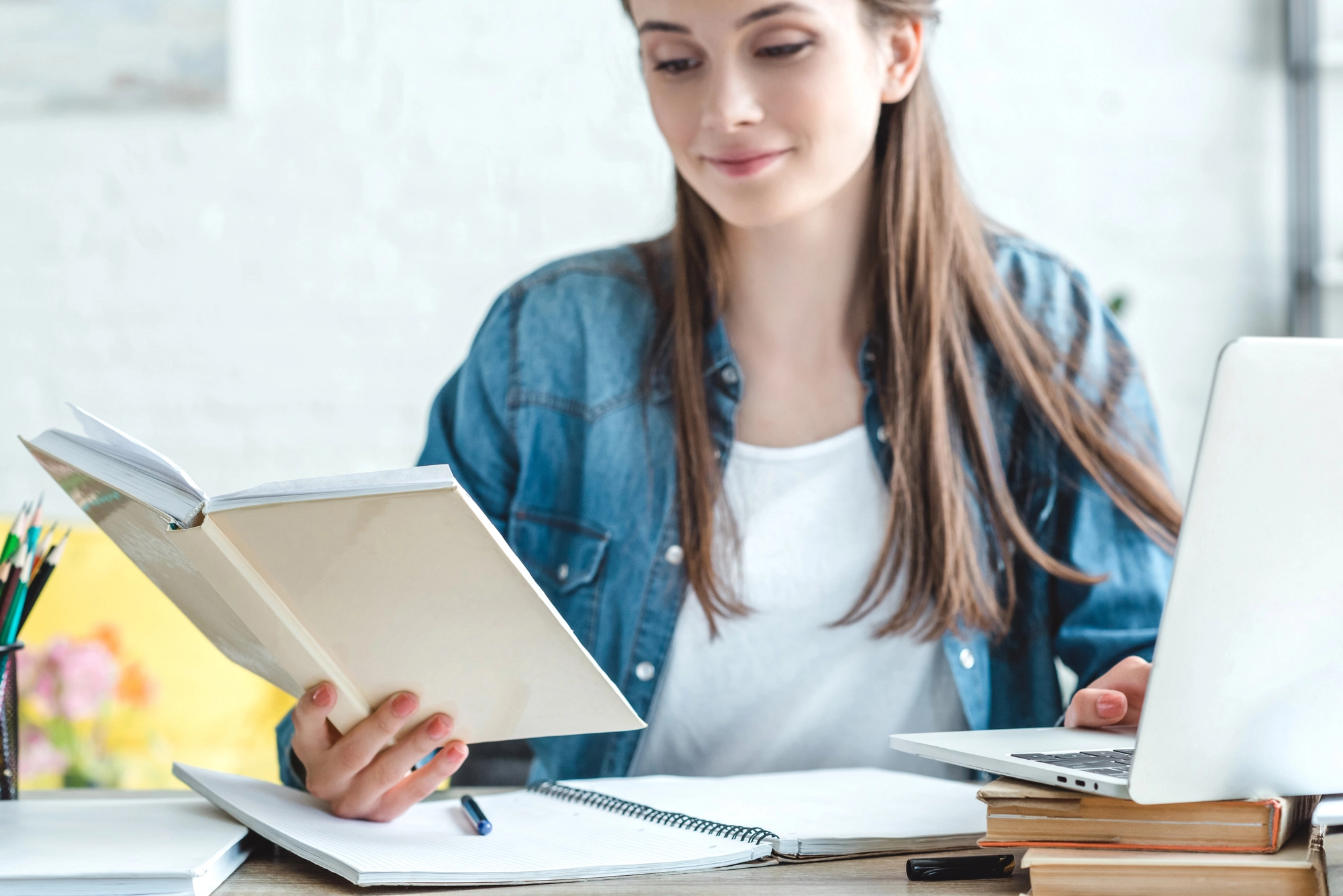 a woman sitting at a table with a laptop and a book