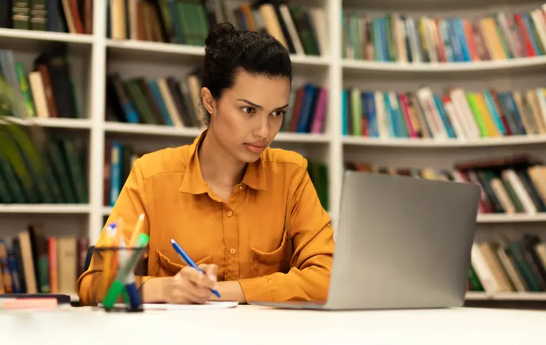 a woman sitting at a desk writing on a notebook