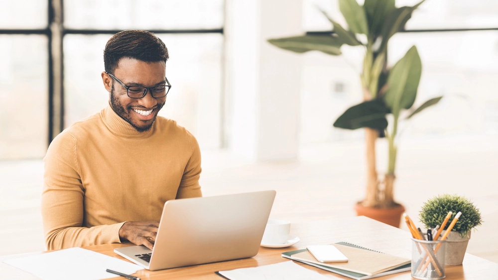 a man smiling at a laptop