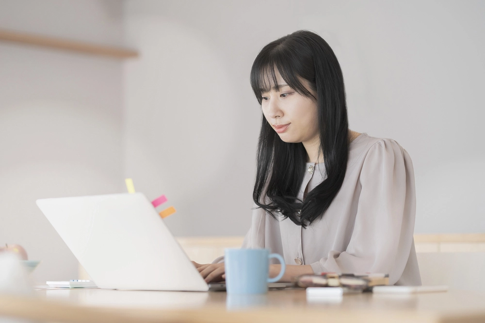a woman sitting at a desk looking at a laptop