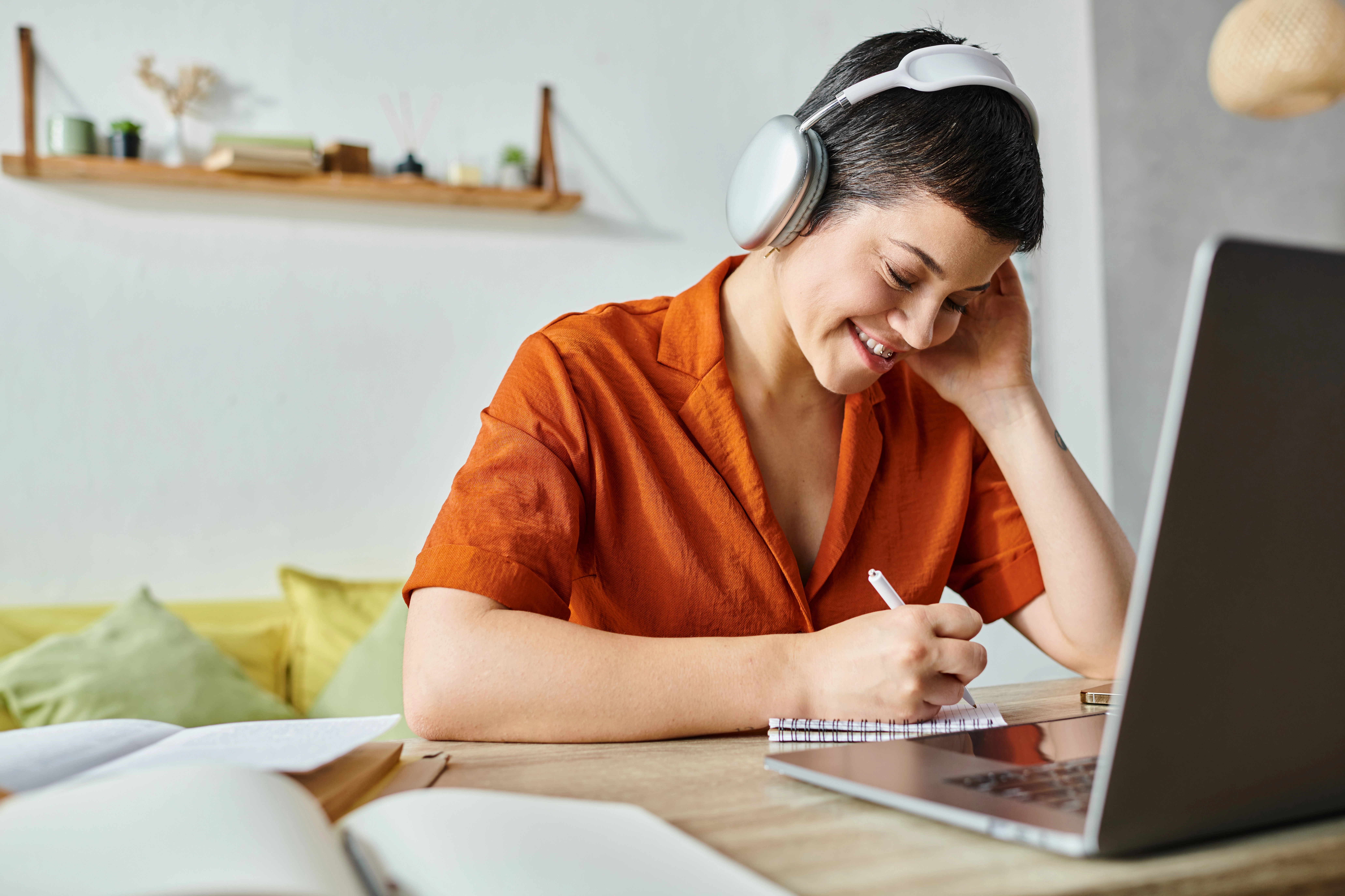 a woman wearing headphones and writing on a notebook