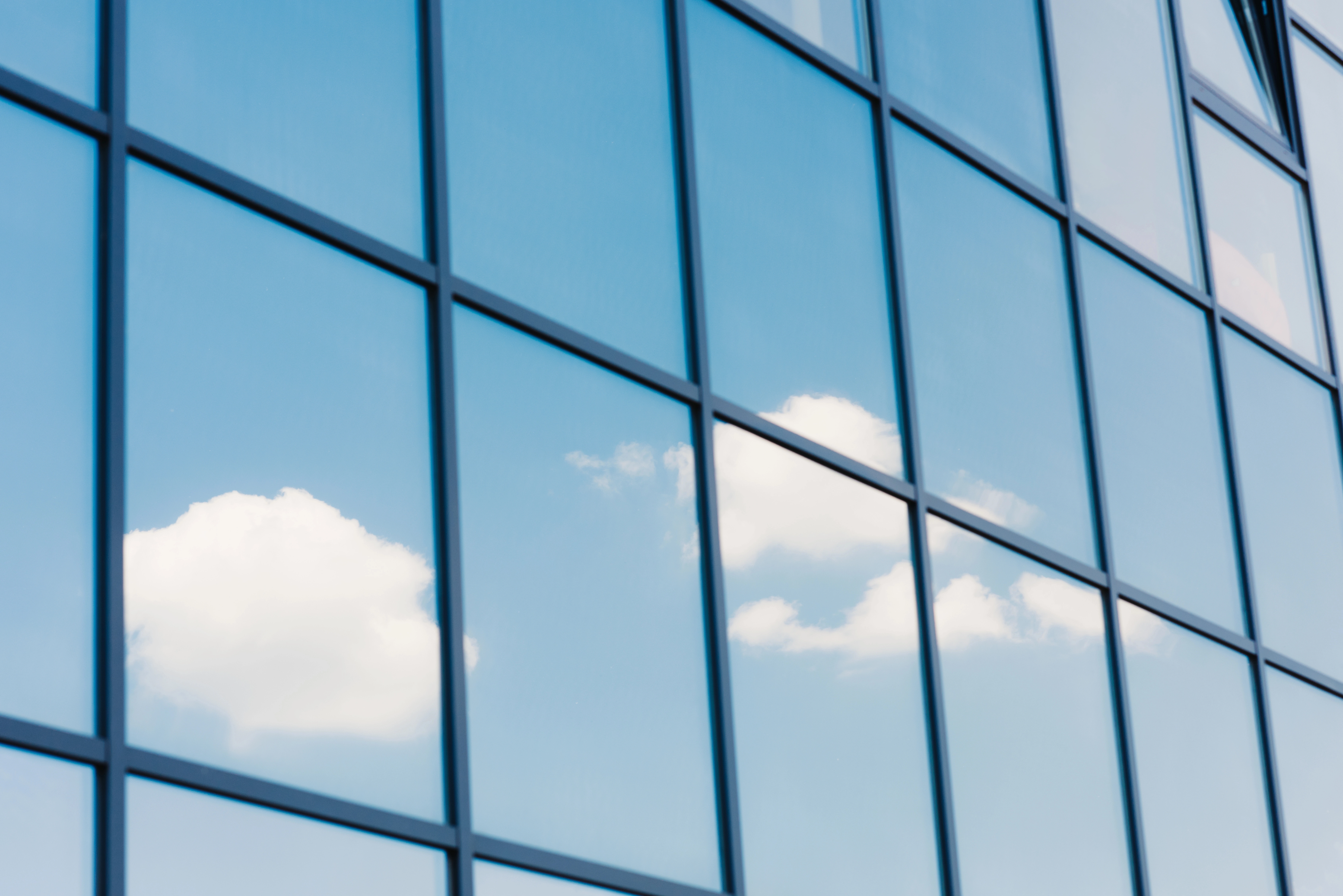 a building with windows and clouds reflected in it