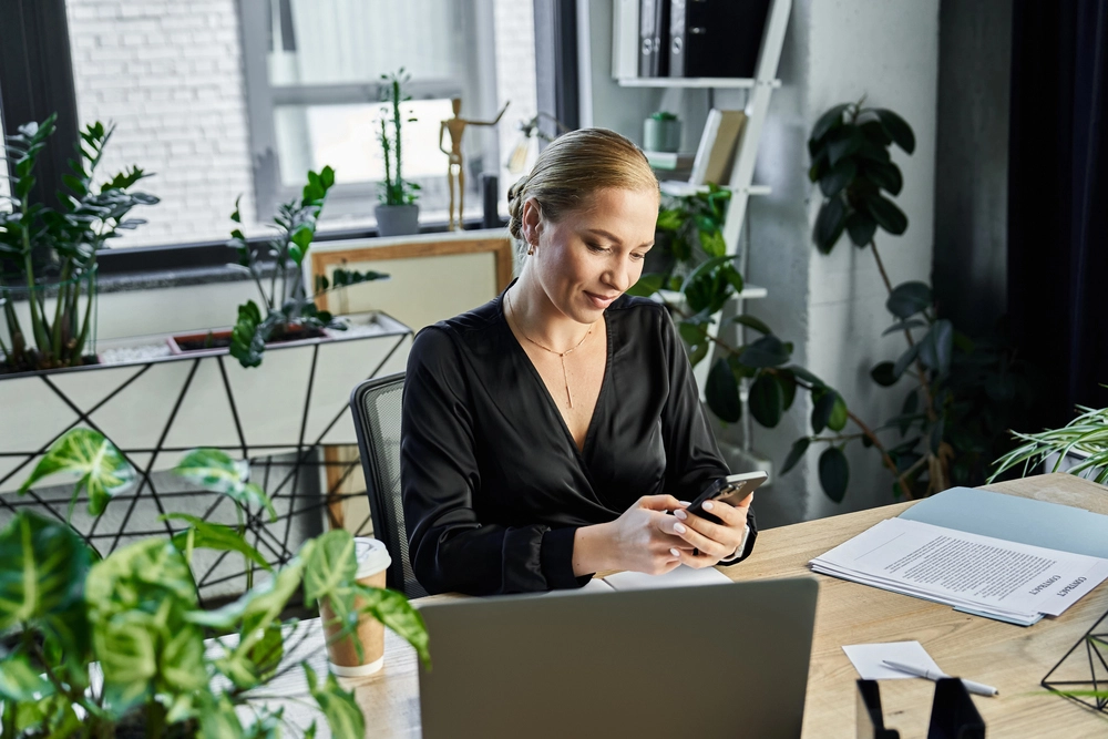 a woman sitting at a desk looking at her phone