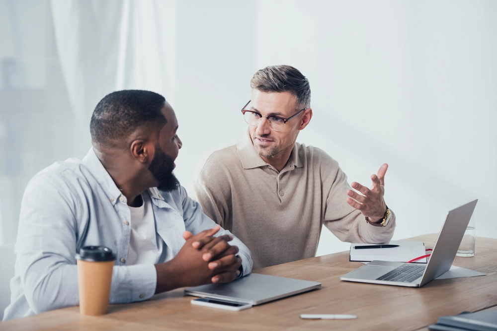 a group of men sitting at a table with a laptop