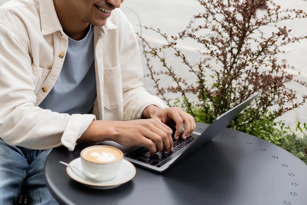 a man sitting at a table with a laptop and a cup of coffee