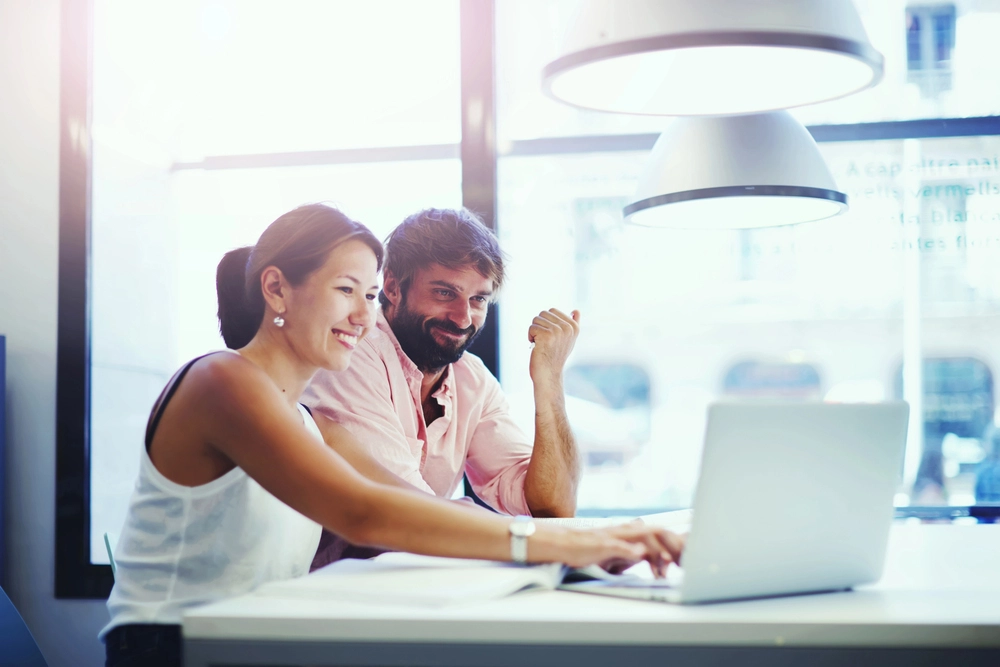 a man and woman looking at a laptop