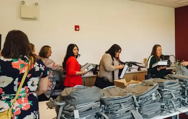 a group of women standing in a room with stacks of bags