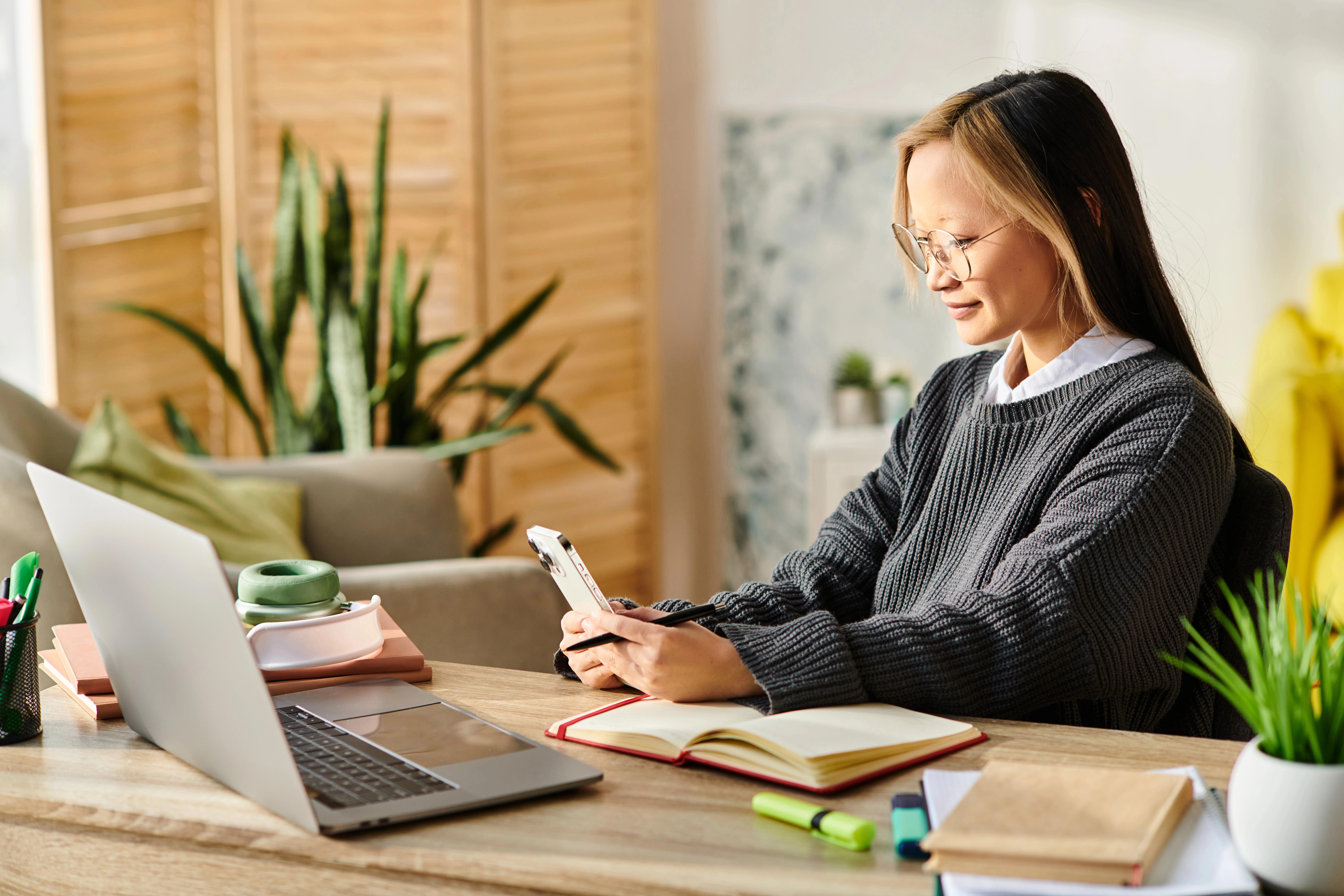 a woman sitting at a desk looking at her phone