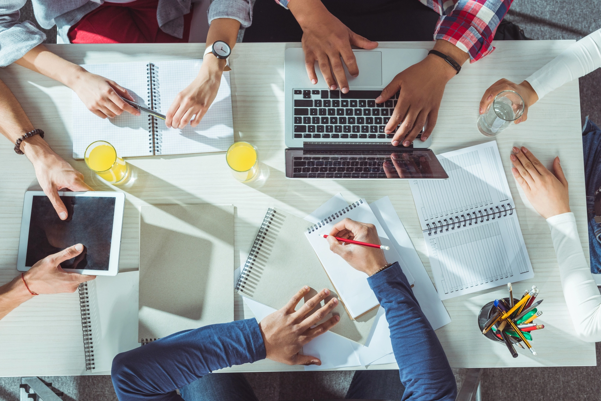 a group of people sitting around a table with notebooks and a laptop