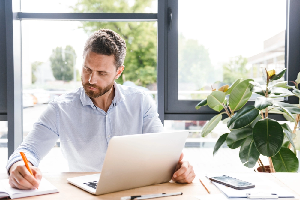 a man sitting at a desk with a laptop