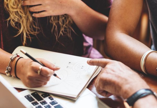 Getting Started A photo of students discussing around a table with laptop and a notebook.