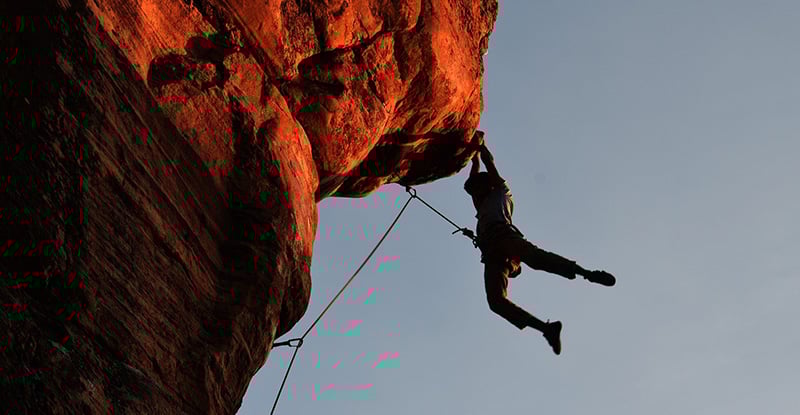 Got Motivation? A photo of a person hanging off the side of a mountain with safety ropes attached.