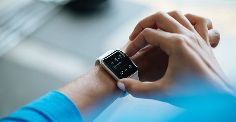 Practical tactics and time-saving tools: Part 2 An overhead photo of a person wearing a blue sweater is seen adjusting their smartwatch.