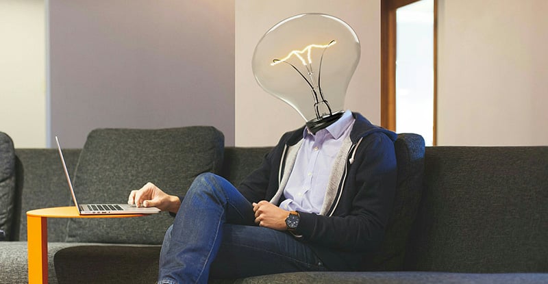 Picture This: DAIS & Power BI A photo of a person typing on a laptop but the head is replaced by a light bulb.