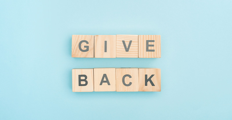 Congrats! You’ve Got Your CPA, Now What? A photo of a light blue background with letter blocks that read " Give back".
