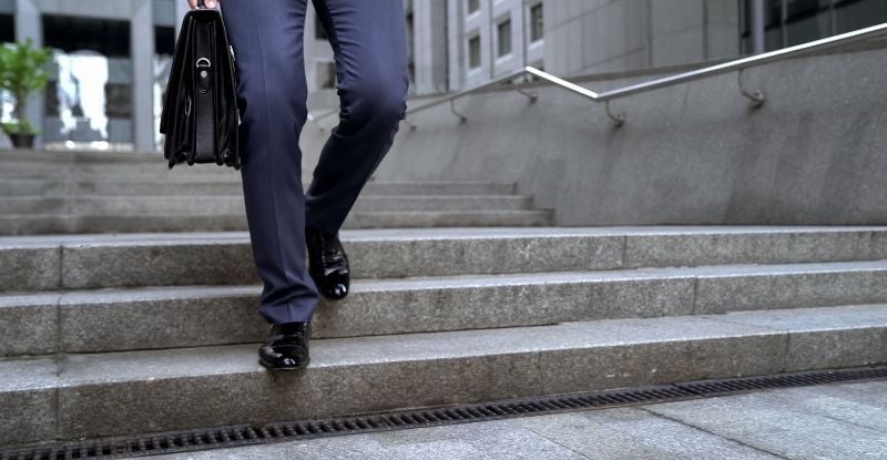 Am I eligible for a Temporary Program Leave? A photo of a man with a brief case climbing down the stairs outside an office building.