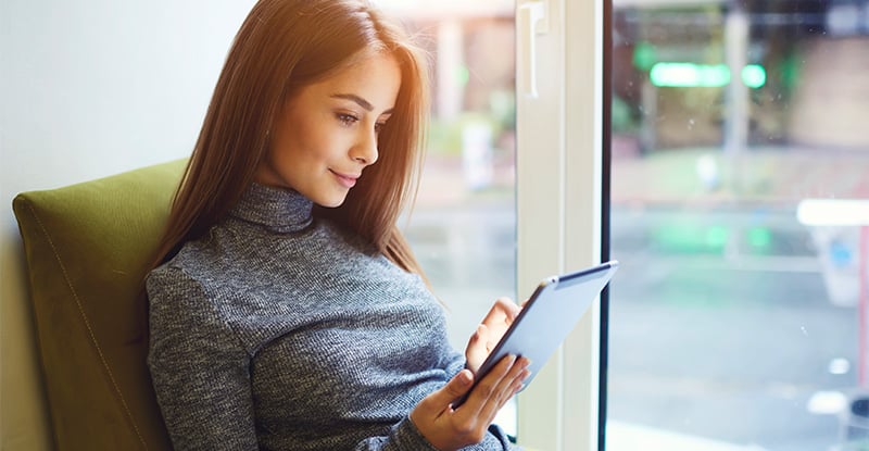 Am I eligible to study in CPA PEP as a temporary resident? A Caucasian woman is lounging on a couch and looking at a tablet in her hands.