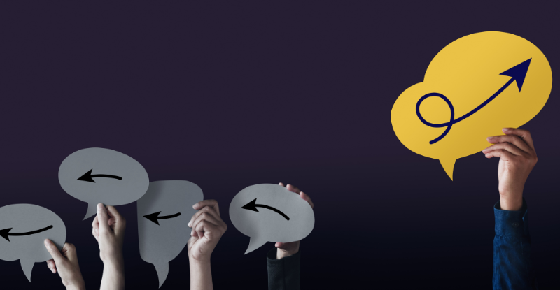 A photo of people holding arrows drawn on a white paper that is in the shape of a cloud all pointing in one direction; whereas, there is an arrow on a yellow paper in the shape of a cloud point in an opposite direction.