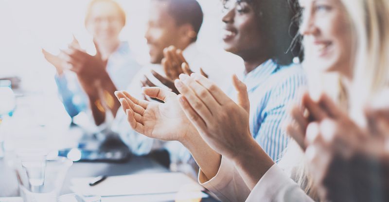 A photo of a group of people clapping their hands in celebration.
